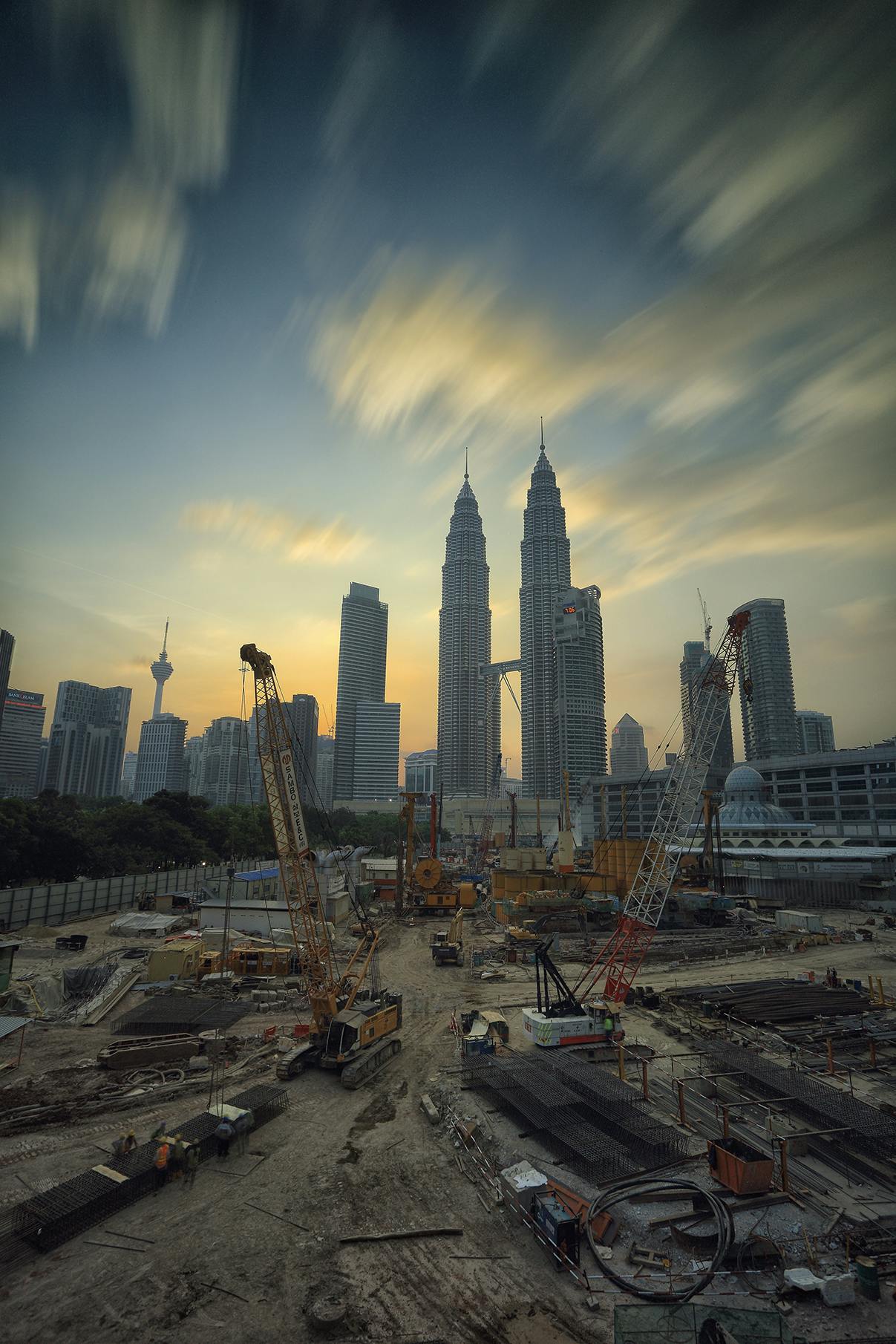 pexels photo 190417 190417 Dramatic view of the Petronas Towers towering over a busy construction site in Kuala Lumpur at sunset.